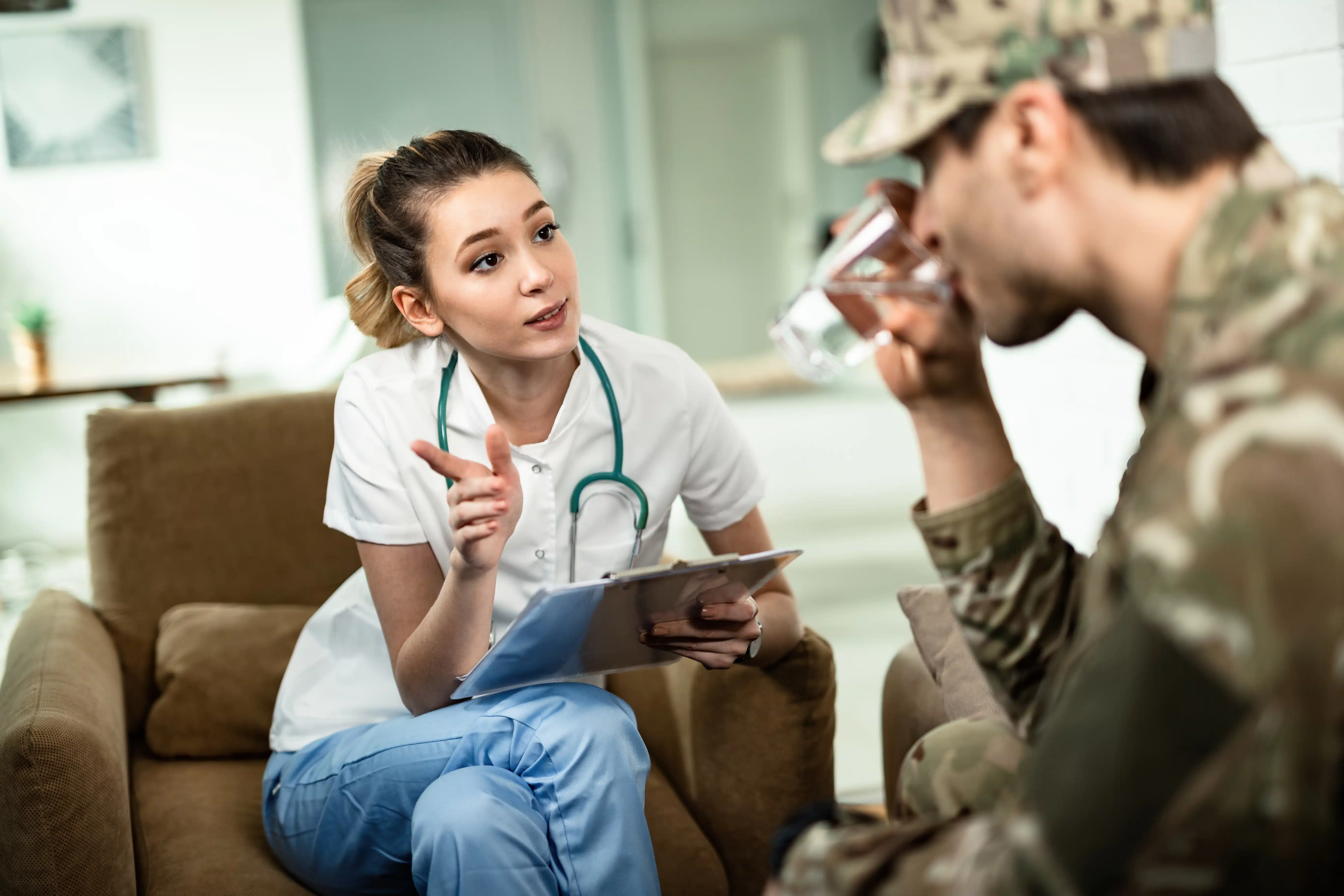 Female doctor talking a soldier about his medical reports while visiting him at home.